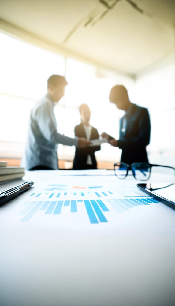 Business valuation meeting image with paperwork displaying graphs on table